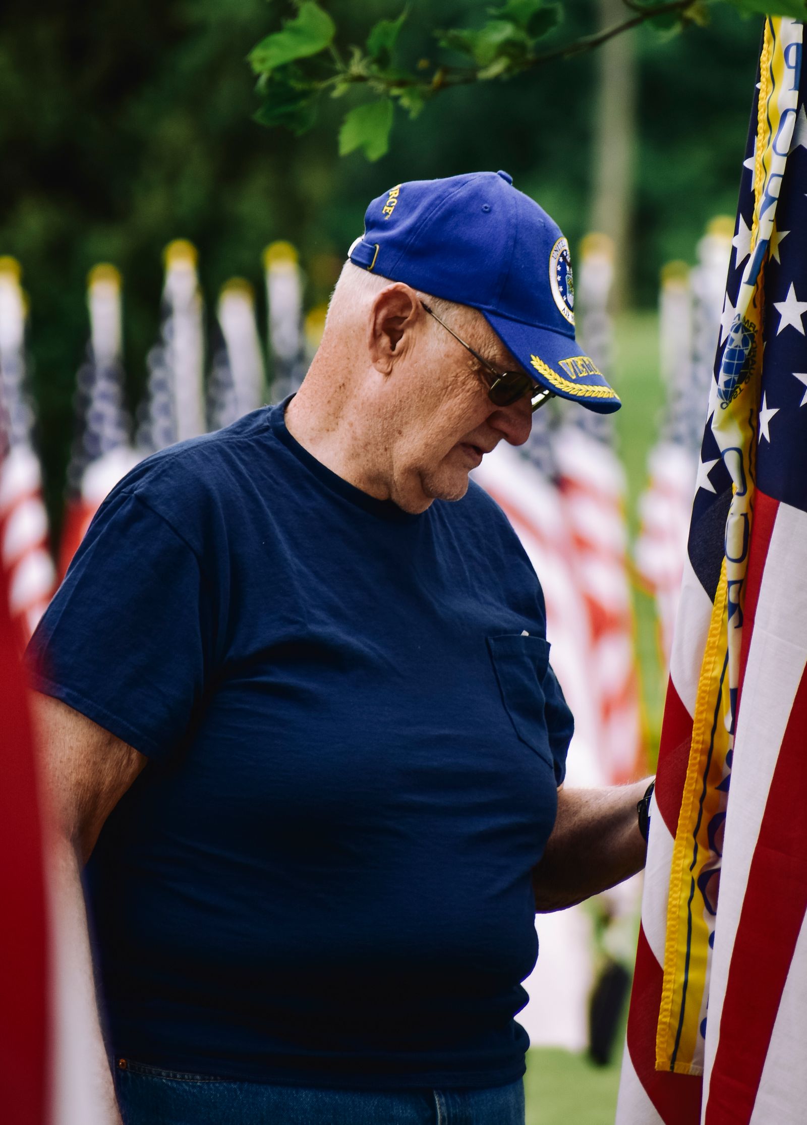 A senior military veteran at home with his daughter and a Purple Haven caregiver, a folded American flag beside them